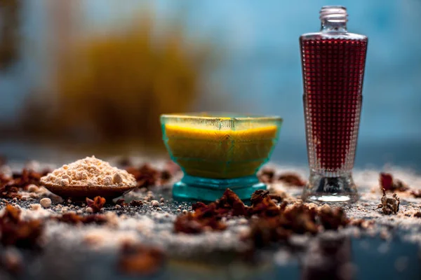 Face mask for skin whitening on wooden surface consisting of besan or gram flour and some rose water. With some dried rose petals and gram flour spread on the surface.