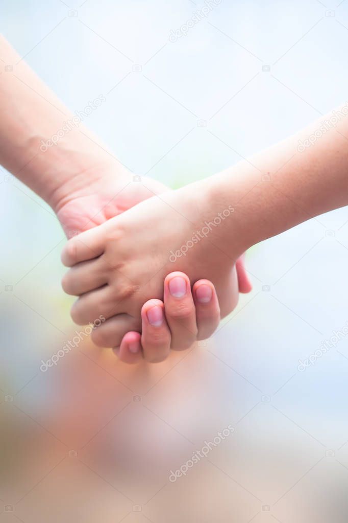 Hand of female child holding the hand of matured man, Shot with blurred background. Concept of Fathers day, Men helping the female hand to overcome conquer obstacles and fears. Vertical shot.