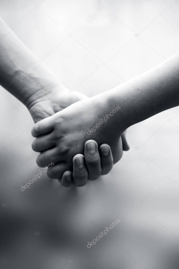 Hand of female child holding the hand of matured man, Shot with blurred background. Concept of Fathers day, Men helping the female hand to overcome conquer obstacles and fears, Vertical shot.