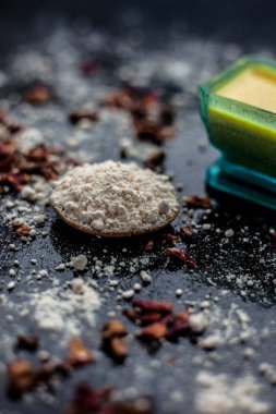 Besan veya gram un ve bazı gül suyu oluşan ahşap yüzey üzerinde cilt beyazlatma için yüz maskesi. Bazı kurutulmuş gül yaprakları ve yüzeyde gram un yayıldı. Dikey çekim.