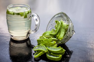 Onunla tüm ham maddeler ile birlikte Aloe Vera Detox içecek içeren ahşap yüzey üzerinde cam kupa yakın. Bulanık arka planda yatay çekim.