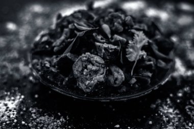 Ahşap yüzey yani Patra veya Paatra esas Colocasia esculenta veya arbi ke Pan veya fil kulak yaprakları ve baharatlar oluşan bir cam plaka ünlü Hint & Gujarati snack çanak. Yatay çekim.