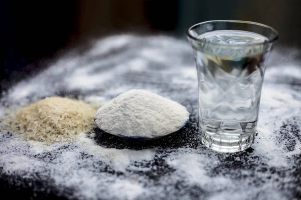 stock image Rice water in a glass bowl along with rice grains & its powder also on wooden surface & some rice power spread on the surface for the treatment of various things such as Home Remedy,Beauty & Health.