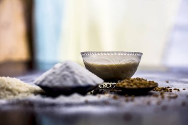 Ahşap yüzeyde pirinç unu suyu ve çemen/kişniş/maydanoz tohumu tozunun saç büyüme çaresi ve yüzeye yayılmış bazı pirinç unu ile cam bir kapta macunu.