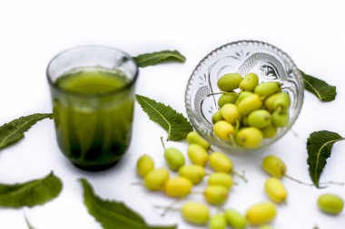Bir cam kase bazı neem meyve veya nimbodi veya nimbudi ile birlikte beyaz izole bir bardak neem meyve detoks veya detoks meyve içeceği.