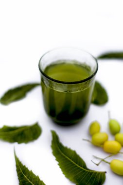 Bir cam kase bazı neem meyve veya nimbodi veya nimbudi ile birlikte beyaz izole bir bardak neem meyve detoks veya detoks meyve içeceği.