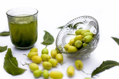 Bir cam kase bazı neem meyve veya nimbodi veya nimbudi ile birlikte beyaz izole bir bardak neem meyve detoks veya detoks meyve içeceği.