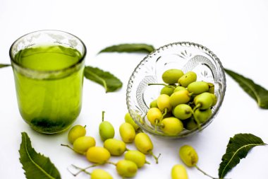 Detoks veya bir cam kase bazı neem meyve veya nimbudi ile birlikte beyaz izole bir bardak neem meyve detoks içki. Yatay atış.