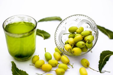 Detoks veya bir cam kase bazı neem meyve veya nimbudi ile birlikte beyaz izole bir bardak neem meyve detoks içki. Yatay atış.
