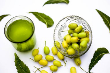 Detoks veya bir cam kase bazı neem meyve veya nimbudi ile birlikte beyaz izole bir bardak neem meyve detoks içki. Yatay atış.