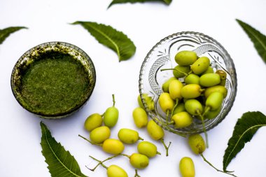 Neem macunu veya nim macunu başka bir kapta neem meyve ile birlikte beyaz izole bir cam kase ve bazı yaprakları da.