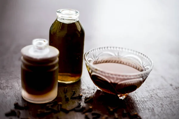 Face mask of clove oil on wooden surface consisting of clove oil and olive oil for the treatment of cleaning dirt and black heads from the skin.