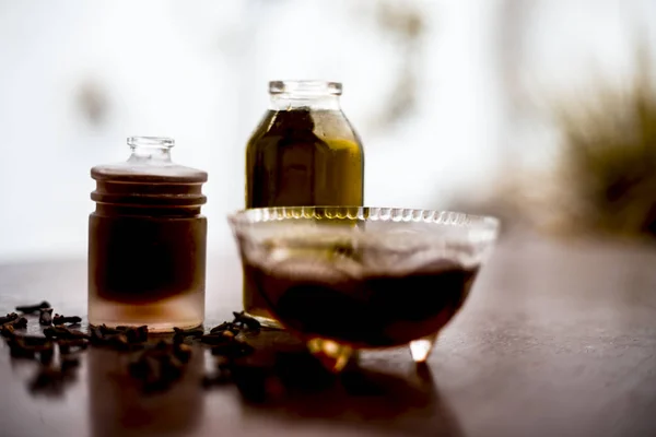 Face mask of clove oil on wooden surface consisting of clove oil and olive oil for the treatment of cleaning dirt and black heads from the skin.