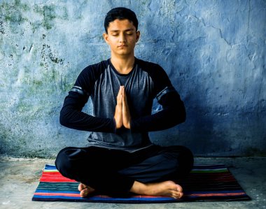 Kolay Pose veya Sukhasana siyah kıyafetleri giyerek renkli mat yapıyor genç bir adam tarafından gerçekleştirilen.