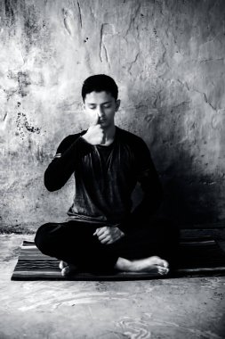 Siyah kıyafetleri giyen renkli bir mat Pranayama veya Pranayam veya nefes kontrol yoga yapan genç adamın portre çekimi.