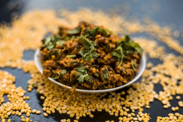 Koyu yüzeyde plaka ıspanak ile kavrulmuş dal Ünlü Hint Punjabi çanak 