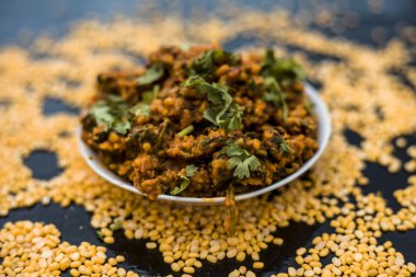 Koyu yüzeyde plaka ıspanak ile kavrulmuş dal Ünlü Hint Punjabi çanak 