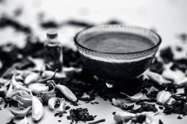 Neem Hint Leylak yüz maskesi beyaz yüzeyde şişe hindistan cevizi yağı ile kase ve sarımsak karanfil macun bırakır 