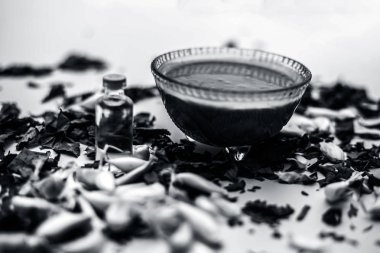 Neem Hint Leylak yüz maskesi beyaz yüzeyde şişe hindistan cevizi yağı ile kase ve sarımsak karanfil macun bırakır 