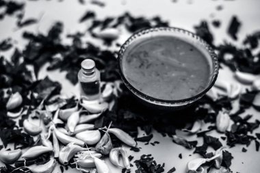 Neem Hint Leylak yüz maskesi beyaz yüzeyde şişe hindistan cevizi yağı ile kase ve sarımsak karanfil macun bırakır 