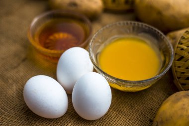 patates suyu iyi ahşap yüzeyüzerinde çiğ patates ve yumurta boyunca kaselerde bal ve yumurta sarısı ile karışık, bir saç kremi yanı sıra saç büyüme organizatörü olarak hareket edecek ev yapımı çok yönlü saç büyüme ilaç kavramı 