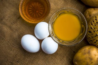 patates suyu iyi ahşap yüzeyüzerinde çiğ patates ve yumurta boyunca kaselerde bal ve yumurta sarısı ile karışık, bir saç kremi yanı sıra saç büyüme organizatörü olarak hareket edecek ev yapımı çok yönlü saç büyüme ilaç kavramı 
