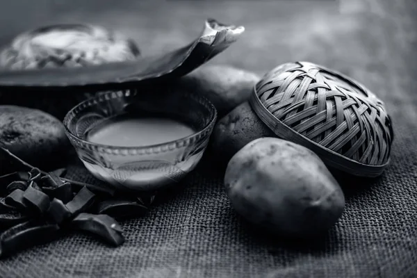 potatoes juice well mixed with aloe vera gel in glass bowl along raw potatoes and aloe vera leaves on jute bag surface, concept  of homemade conditioner and shampoo for dandruff and scalp cleaning