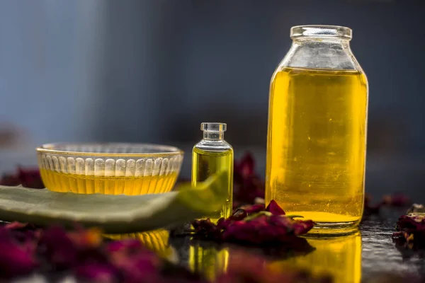 herbal oils mask in glass bowl to fight dandruff with bottles of castor oil and tea tree oil with aloe vera leaf on wooden surface