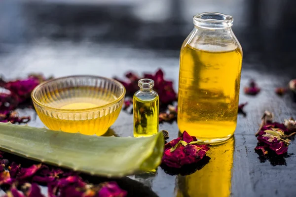 herbal oils mask in glass bowl to fight dandruff with bottles of castor oil and tea tree oil with aloe vera leaf on wooden surface