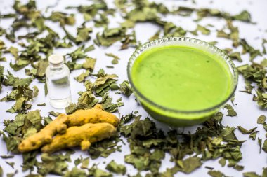 Neem Hint Leylak yüz maskesi beyaz yüzeyde şişe hindistan cevizi yağı ile kuru ciltler için kase de macun ve zerdeçal tozu bırakır 