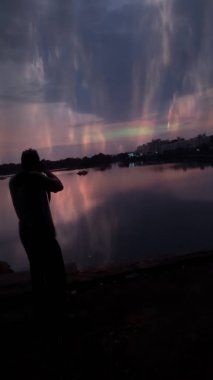 Genç bir siluet ile dağlar, bulutlar ve fantezi renkler ile çekilen gündoğumu zamanı.