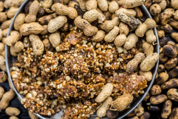 silver plate with chikki with roasted peanuts on wooden surface, close-up