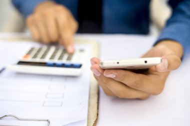 hesap makinesi ile akıllı telefon kullanırken denetçi muhasebe finans ve kredi ile ilgili iş ve yüzeyde sayfaları ve kalem ile masada oturan 