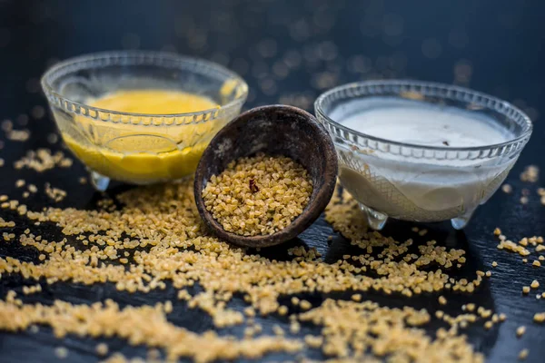 bowls with yogurt and raw oats with well mixed raw turmeric on wooden surface, ingredients for oats face mask