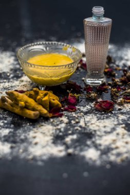 deri pH korumak için gram un yüz maskesi yapmak için masada cam kase içinde zerdeçal ve gül suyu ile karışık nohut unu