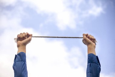 Elinde paslı zincir ile mavi renkli takım elbise ve siyah renkli kravat giyen genç bir işadamı nın yakın yükseltilmiş elleri. Suçlu, suç ve teslimiyet kavramı.
