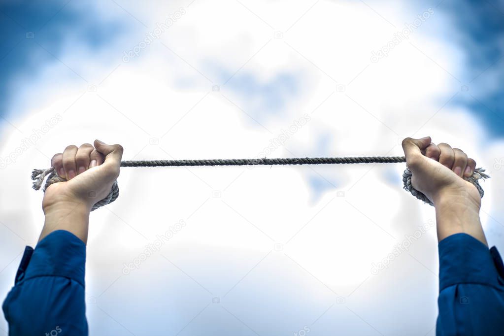 Close upraised hands of a young businessman wearing a blue colored suit and black colored necktie with rusted chain in his hands. Concept of guilty, crime and surrender.