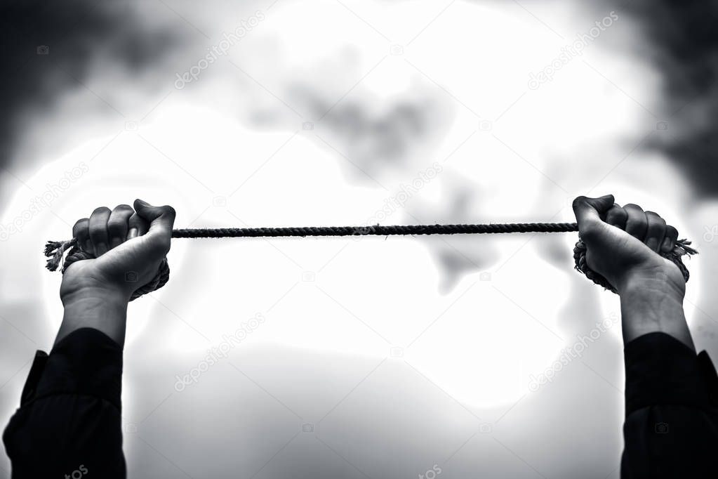 Close upraised hands of a young businessman wearing a blue colored suit and black colored necktie with rusted chain in his hands. Concept of guilty, crime and surrender.