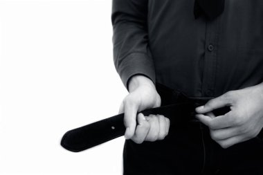 Beyaz üzerine izole edilmiş mavi renkli gömlek ve kot pantolon giyen ve siyah pantolon ya da pantolonunu giyen/kapatan ya da büken bir işadamının yarım uzunlukta ki fotoğrafı. Beyaz üzerine izole.