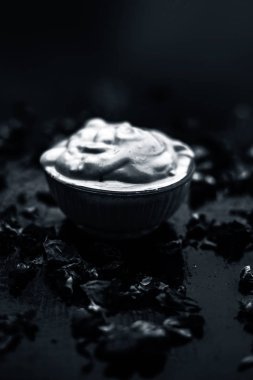 Ahşap yüzeyde yağlı cildin tedavisi için gül yaprakları ile kasede Multani mitti oluşan ubtan yüz maskesi 