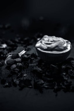 Ahşap yüzeyde yumuşak cilt tedavisi için kase de bentonit kil ile süt ve badem oluşan Multani mitti yüz maskesi 