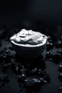 Ahşap yüzeyde yağlı cildin tedavisi için gül yaprakları ile kasede Multani mitti oluşan ubtan yüz maskesi 