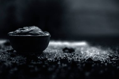 Ahşap yüzeyde yağlı cildin tedavisi için gül yaprakları ile kasede Multani mitti oluşan ubtan yüz maskesi 