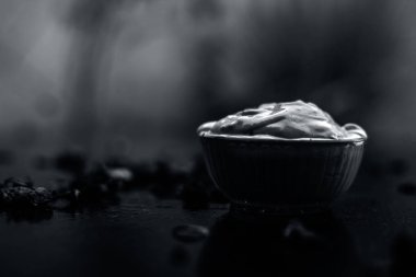 Ahşap yüzeyde yağlı cildin tedavisi için gül yaprakları ile kasede Multani mitti oluşan ubtan yüz maskesi 