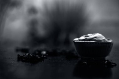 Ahşap yüzeyde yağlı cildin tedavisi için gül yaprakları ile kasede Multani mitti oluşan ubtan yüz maskesi 