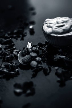 Ahşap yüzeyde yumuşak cilt tedavisi için kase de bentonit kil ile süt ve badem oluşan Multani mitti yüz maskesi  