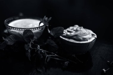 Ahşap yüzeyüzerinde yeşil yaprakları olan kaselerde yoğurt ve multani mitti oluşan koyu lekelerin tedavisi için ev yapımı Diy yüz maskesi 