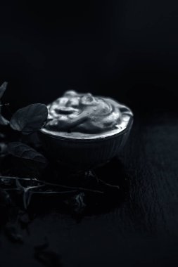 Ahşap yüzeyüzerinde yaprakları ile kase yoğurt ve multani mitti oluşan koyu lekeler tedavi için ev yapımı Diy yüz maskesi 