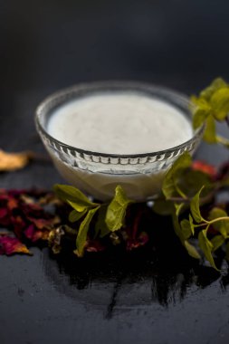 yoğurt oluşan koyu yamalar ve ahşap yüzey üzerinde yaprakları ile kase de tedavi için hazırlık ev yapımı Diy yüz maskesi için malzemeler 