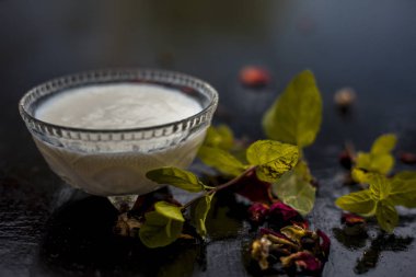 yoğurt oluşan koyu yamalar ve ahşap yüzey üzerinde yaprakları ile kase de tedavi için hazırlık ev yapımı Diy yüz maskesi için malzemeler 